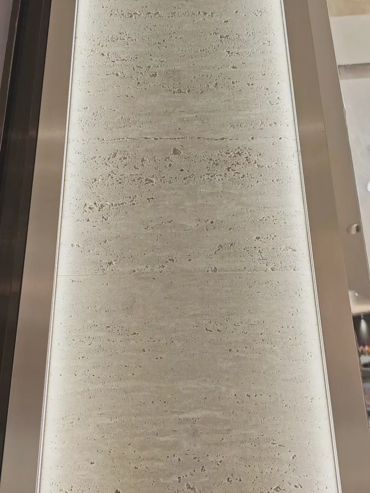 门头 · 洞石柔性石材 · 眼镜店 门头 打印洞石4：洞石 孔洞肌理有实际起伏，斜射光下出现阴影层次，现场实拍