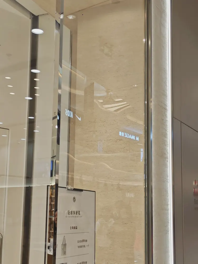 门头 · 洞石柔性石材 · 眼镜店 门头 打印洞石2：洞石 孔洞肌理有实际起伏，斜射光下出现阴影层次，现场实拍
