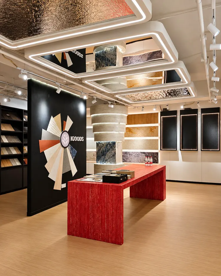 艾谷思成都展厅：成都展厅全景与红色洞石选材长桌。红色选材长桌采用柔性石材打印系列红色洞石，后方可见品牌形象墙与圆柱样板装置。
