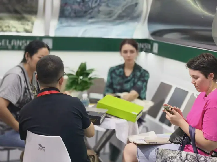 展位洽谈：艾谷思团队成员与客户在展位内会谈，桌面摆放产品资料