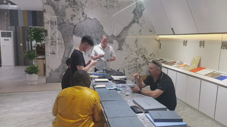 展位造型墙：中式月亮门造型与材料样板结合，工作人员与访客交流